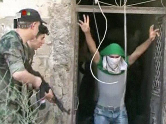 Image de la télévision d'Etat syrienne montrant un jeune homme au visage dissimulé supposé se rendre aux forces gouvernementales à Alep © KEYSTONE/AP Syrian State TV/UNCREDITED