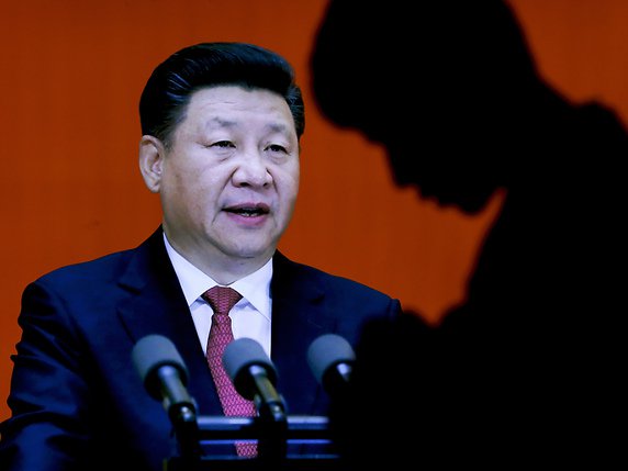 En ombre chinoise, un homme passe devant le secrétaire général du PCC Xi Jinping, également président de la République. © KEYSTONE/AP/ANDY WONG