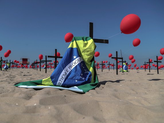 Sur la plage de Copacabana, à Rio, l'ONG Rio de Paz a organisé samedi matin un lâcher de 1000 ballons rouges en hommage aux personnes décédées du Covid-19 au Brésil, avec 100 croix noires plantées dans le sable. © KEYSTONE/EPA/Antonio Lacerda