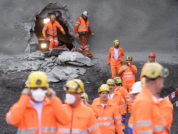 Des ouvriers sortent du tube nord du tunnel de Riedberg dont le percement s'est achevé jeudi. © KEYSTONE/LAURENT GILLIERON