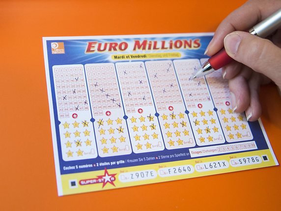 Une personne remplit un billet de loterie "Euro Millions" dans un kiosque. © KEYSTONE/JEAN-CHRISTOPHE BOTT