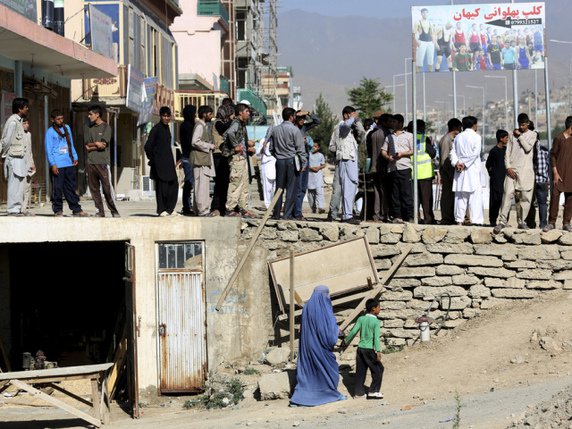 Des Afghans observent le site où a eu lieu l'attentat-suicide