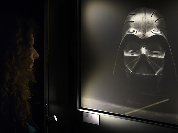 Une personne regarde une photographie d'un masque de Dark Vador dans le cadre de la nouvelle exposition de la Maison d'Ailleurs, "Je suis ton père !" à Yverdon-les-Bains (VD) © KEYSTONE/LAURENT GILLIERON