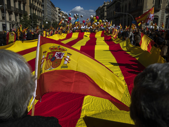 Des milliers de personnes opposées à l'indépendance de la Catalogne ont défilé dimanche dans les rues de Barcelone. Sur la photo. le drapeau espagnol au premier plan fait face à un gigantesque drapeau indépendantiste. © KEYSTONE/AP/EMILIO MORENATTI