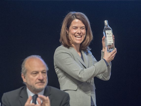 Une bouteille de kirsch zougois offerte à la présidente du PLR, Petra Gössi. Au premier plan, le conseiller national zurichois Filippo Leutenegger. © KEYSTONE/URS FLUEELER