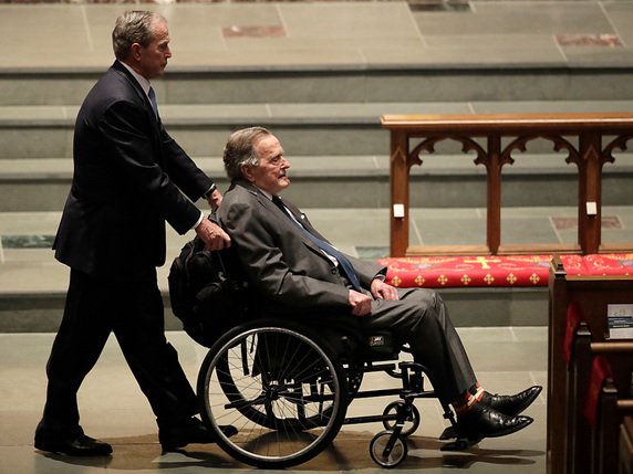 L'ex-président républicain de 1989 à 1993 et vice-président de Ronald Reagan George H.W. Bush est atteint de la maladie de Parkinson, ce qui le contraint depuis plusieurs années à se déplacer en fauteuil roulant. Ici en compagnie de son fils George W.Bush (archives). © KEYSTONE/AP/DAVID J. PHILLIP