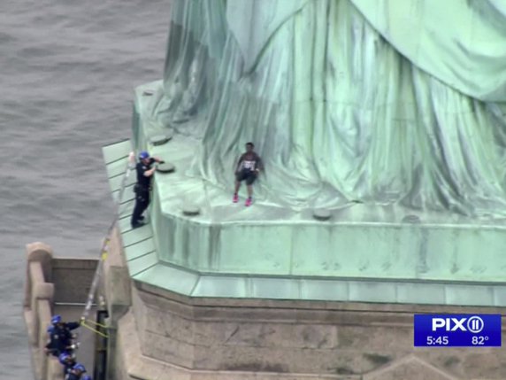 Une femme, juchée en haut du piédestal de la statue de la Liberté à New York, refusait de descendre mercredi. Des officiers en harnais ont fini par l'en déloger. © KEYSTONE/AP PIX11