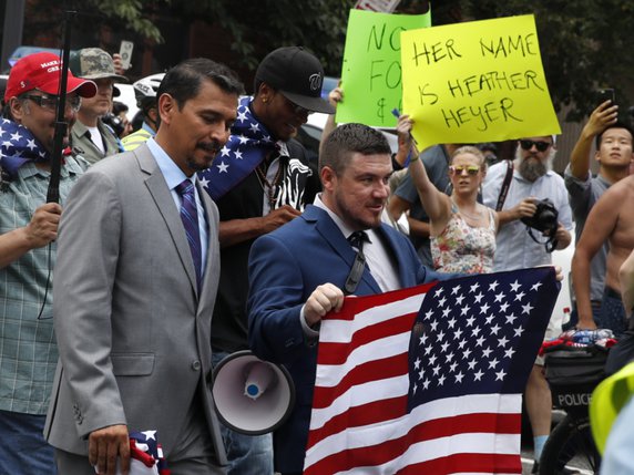 L'organisateur du rassemblement d'extrême droite, Jason Kessler (au centre, avec le drapeau américain), se dirige vers la Maison Blanche, devant des contre-manifestants. © KEYSTONE/AP/JACQUELYN MARTIN