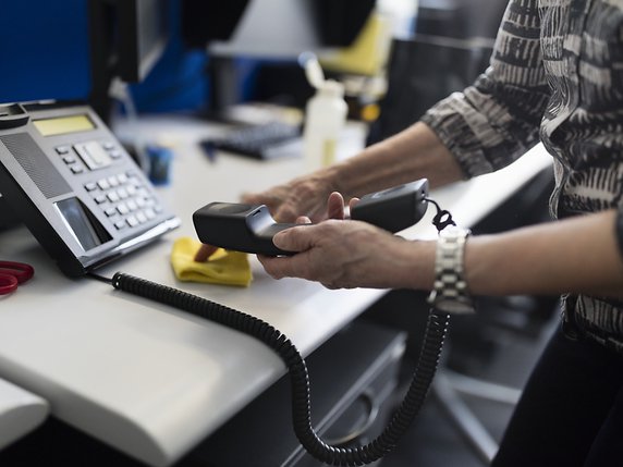 Le travail n'empêche pas toujours la précarité. Ici, une femme nettoyant un téléphone dans un bureau (image d'illustration). © KEYSTONE/GAETAN BALLY