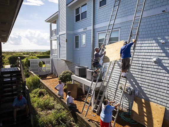 Des habitants de Wrightsville Beach, en Caroline du Nord, se préparent à l'arrivée de l'ouragan en accrochant des planches de bois contre les fenêtres. © KEYSTONE/EPA/JIM LO SCALZO
