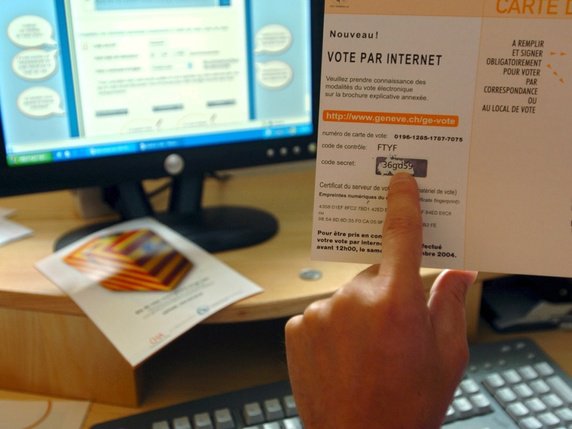 Un électeur contrôle son code secret sur sa carte de vote afin de pouvoir remplir son bulletin sur internet depuis son ordinateur (photo d'illustration). © KEYSTONE/MARTIAL TREZZINI