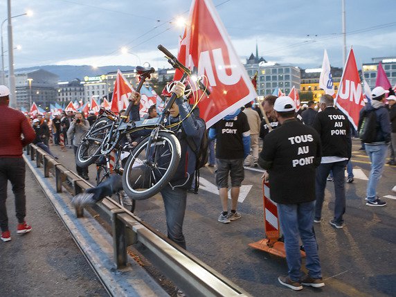 Ce cycliste a réussi à se faufiler parmi les grévistes bloquant le pont du Mont-Blanc. © KEYSTONE/SALVATORE DI NOLFI