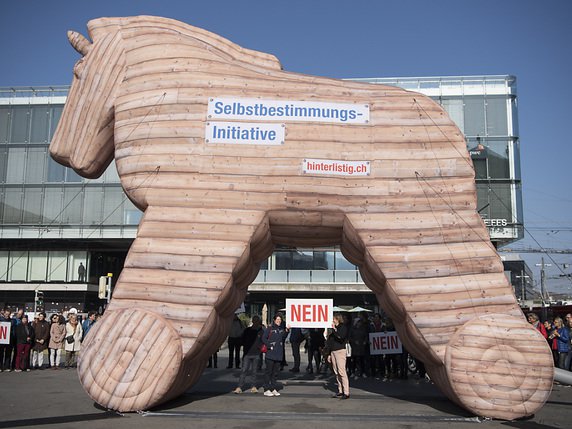 "Un cheval de Troie pour la démocratie et les droits humains": les opposants à l'initiative pour l'autodétermination devant la gare de Berne le 22 octobre dernier. © KEYSTONE/PETER SCHNEIDER