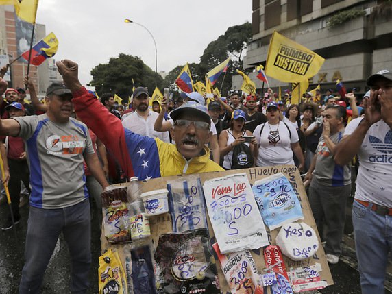 Un manifestant de l'opposition brandit une pancarte qui dénonce l'augmentation des prix des denrées dans le pays. © KEYSTONE/AP/FERNANDO LLANO