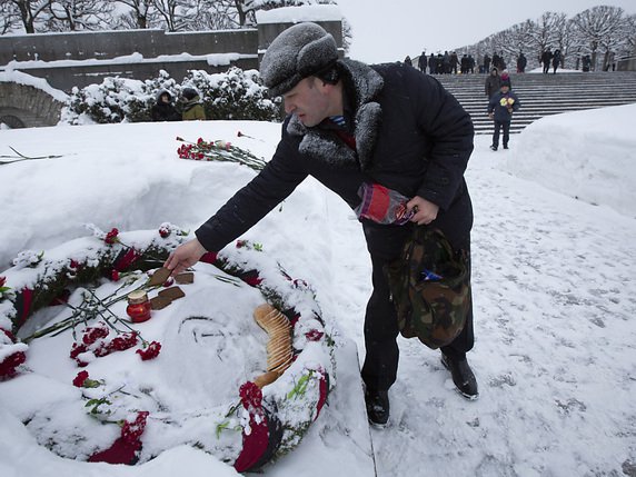 Un homme dépose un morceau de pain en honneur des victimes du siège de Leningrad. © KEYSTONE/AP/DMITRI LOVETSKY