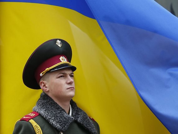 Un soldat ukrainien monte la garde devant un drapeau national à Kiev (archives). © KEYSTONE/EPA/SERGEY DOLZHENKO