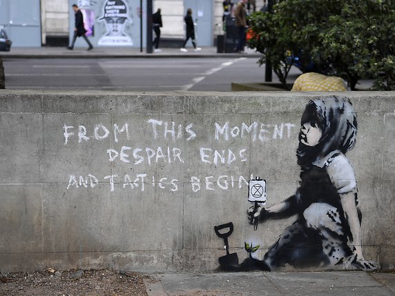 "A partir de maintenant, le désespoir prend fin et la tactique commence", est-il écrit en grandes lettres à côté d'un enfant portant un foulard. Cette peinture murale apparue vendredi à Londres serait l'oeuvre de Banksy. © KEYSTONE/EPA/ANDY RAIN