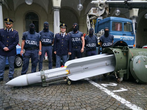 Les forces de l'ordre posent devant le missile découvert dans un hangar aéroportuaire près de Pavie, dans le nord de l'Italie. © KEYSTONE/AP ANSA/TINO ROMANO