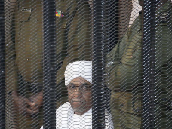 Vêtu d'une robe blanche traditionnelle, l'ancien homme fort du pays Omar el-Béchir a été placé dans une cage en métal comme lors de la première audience. © KEYSTONE/EPA/AMEL PAIN