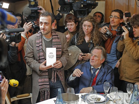 Didier Decoin (assis, costume bleu) avait la charge d'annoncer chaque automne le nom du lauréat du Goncourt. Ici avec Jérôme Ferrari en 2012 (archives). © KEYSTONE/AP/THIBAULT CAMUS
