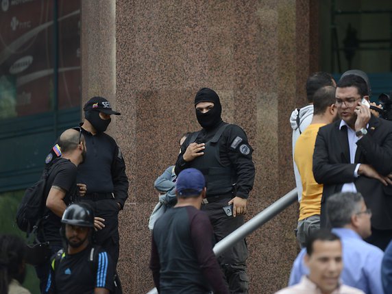 Des agents encagoulés bloquaient mardi l'entrée des bureaux de l'opposant Juan Guaido à Caracas. © KEYSTONE/AP