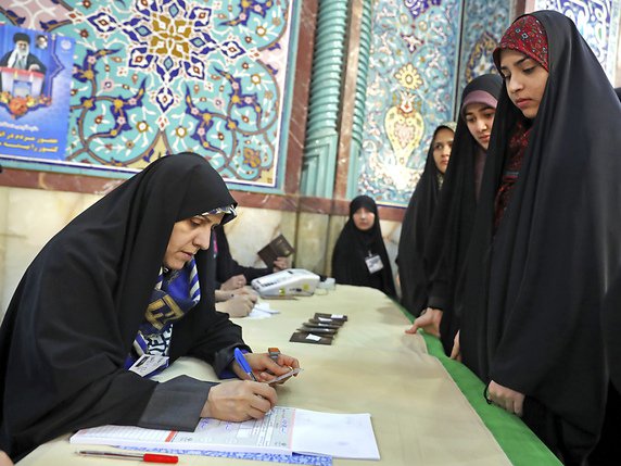 Des votants s'enregistrent pour glisser leur bulletion dans l'urne à Téhéran. © KEYSTONE/AP/Ebrahim Noroozi