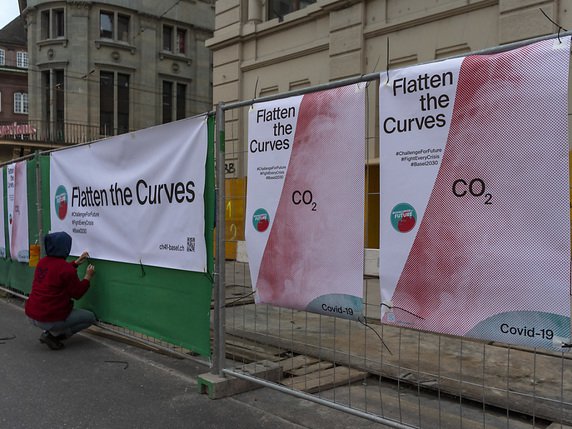 A Bâle, les affiches appelant à aplatir la courbe des émissions de CO2 comme celle du coronavirus se sont multipliées sur les clôtures de chantier. © KEYSTONE/GEORGIOS KEFALAS