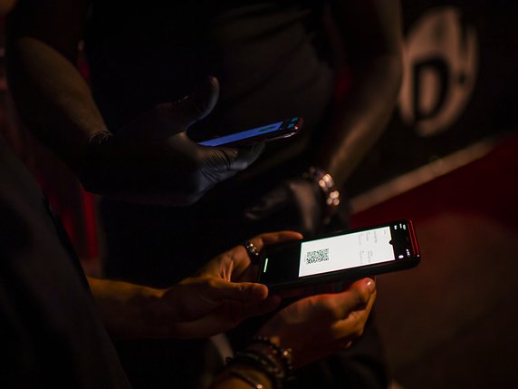 Un agent de sécurité scanne le QR Code de l'application Swiss Pass Night d'un client devant une discothèque à Lausanne  Seules 300 personnes peuvent danser par salle dans la disco et les personnes doivent être inscrites sur le Swiss Pass Night. © KEYSTONE/JEAN-CHRISTOPHE BOTT