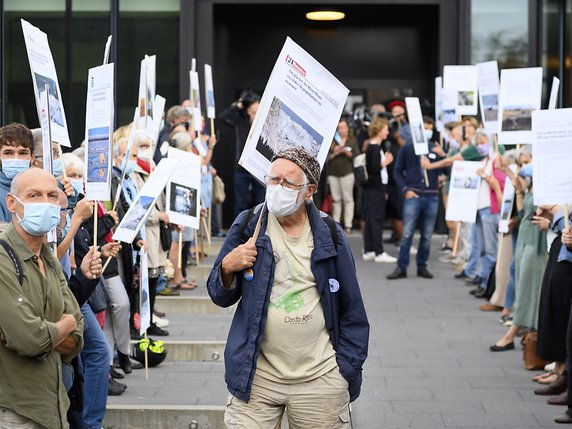 Une petite centaine de personnes, dont le Prix Nobel de chimie Jacques Dubochet (au centre), ont accueilli les militants climatiques mardi matin au tribunal à Renens. © KEYSTONE/LAURENT GILLIERON