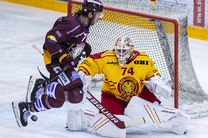 L'attaquant genevois Marc-Antoine Pouliot tente de surprendre le portier des Langnau Tigers, Ivars Punnenovs. © KEYSTONE/MARTIAL TREZZINI