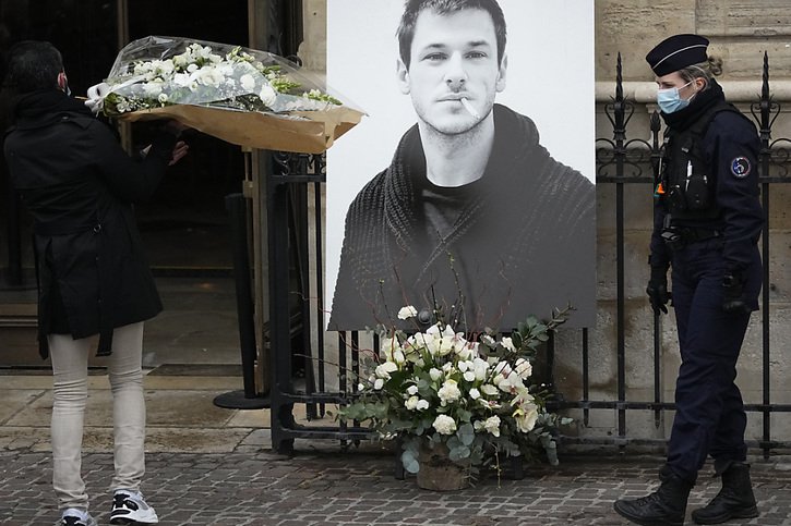 Un homme porte un bouquet de fleurs près d'un portrait de l'acteur français Gaspard Ulliel devant l'Eglise Saint Eustache à Paris jeudi peu avant son service funèbre. © KEYSTONE/AP/Michel Euler