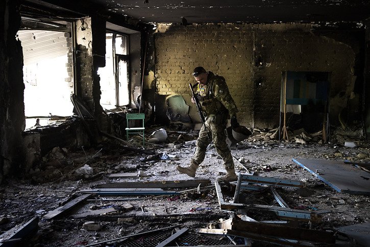 Un militaire ukrainien inspecte une école endommagée dans le village de Vilkhivka dans la banlieue de Kharkiv. La guerre en Ukraine est entrée mardi dans son quatrième mois (archives). © KEYSTONE/AP/Bernat Armangue