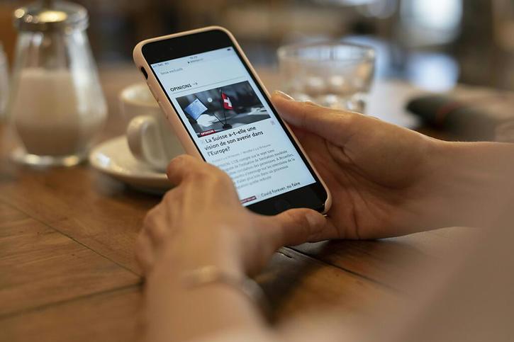 Une personne consulte le journal Le Temps sur son smartphone: de nombreux titres sont utilisés de manière croissante en ligne plutôt que sur papier. © Keystone/STF