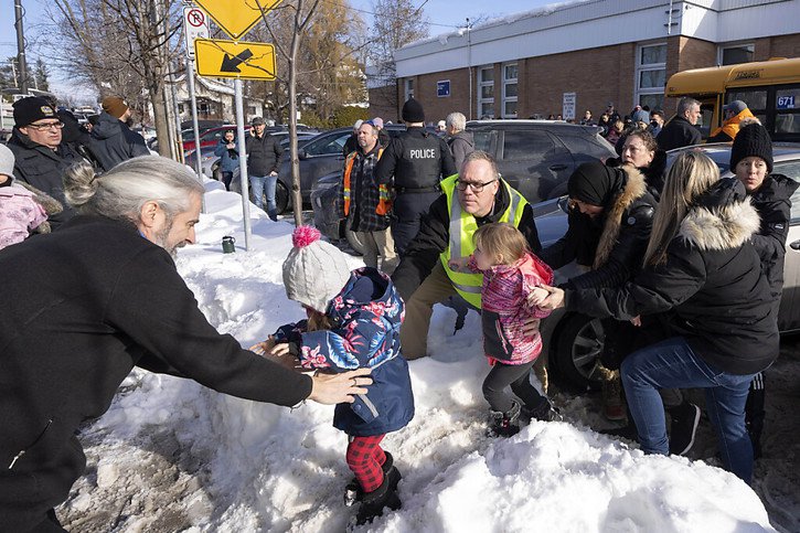 Des parents et leurs enfants sont embarqués dans un bus de secours alors qu'ils attendent des nouvelles après qu'un bus a percuté une crèche à Laval, au Québec, mercredi. © KEYSTONE/AP/Ryan Remiorz