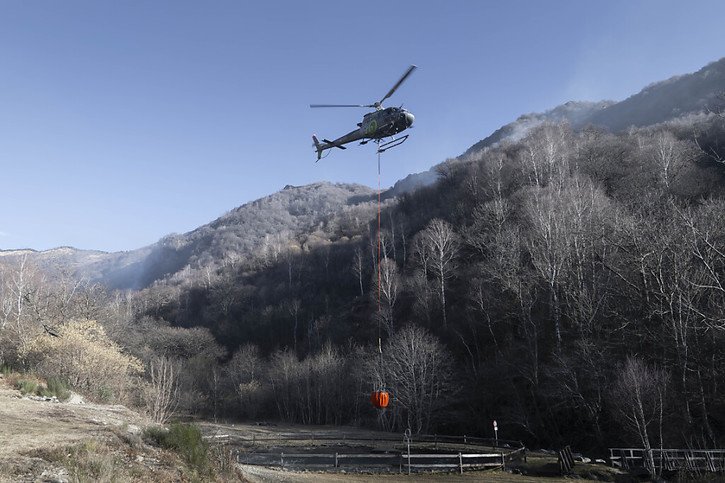 Grâce à l'intervention notamment des hélicoptères, l'incendie qui s'est déclaré vendredi soir dans le Malcantone, a été sous contrôle samedi à la mi-journée. © KEYSTONE/TI-PRESS/Pablo Gianinazzi